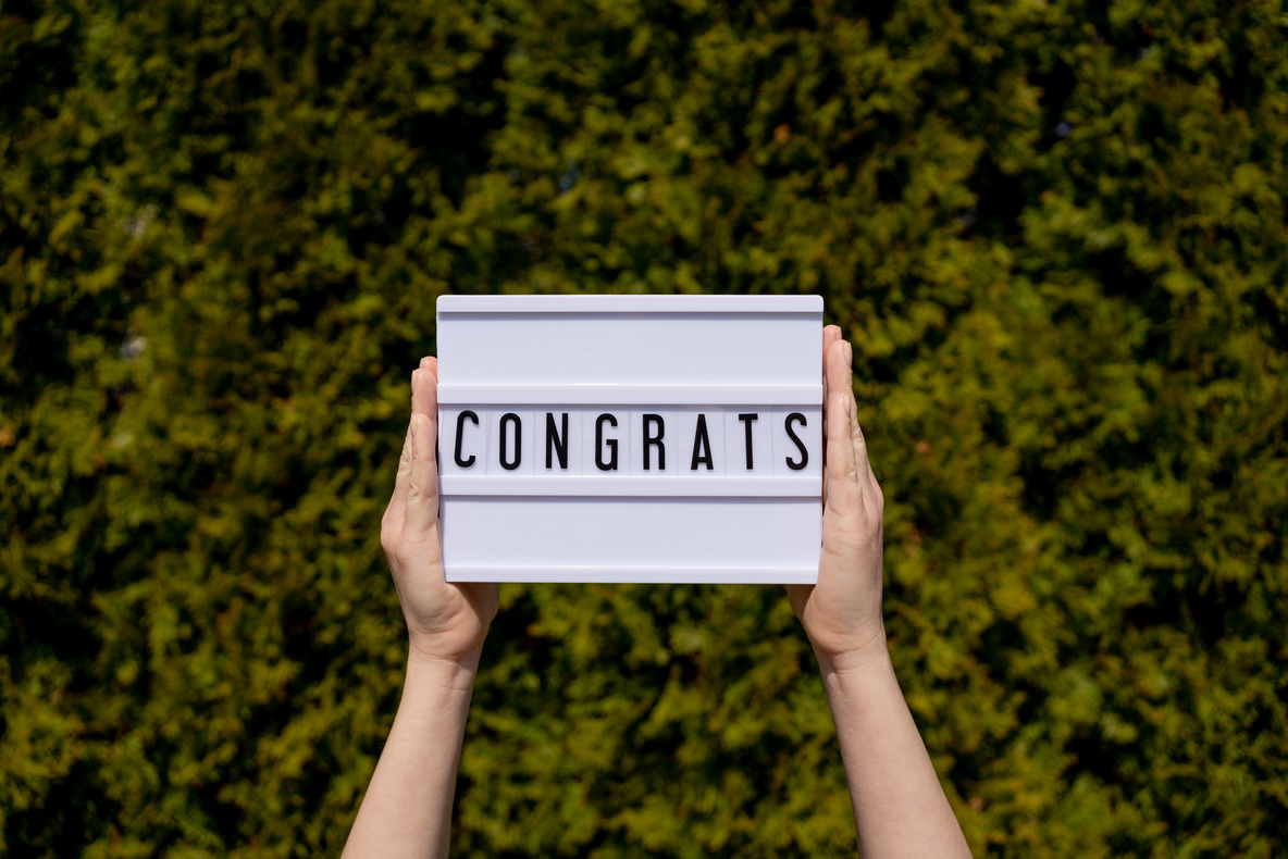 Woman holding sign writing "congrats"
